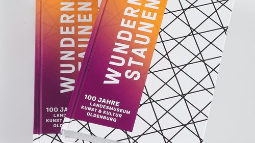 Zwei gestapelte Ausstellungskataloge „Wundern & Staunen – 100 Jahre Landesmuseum Kunst & Kultur Oldenburg” 