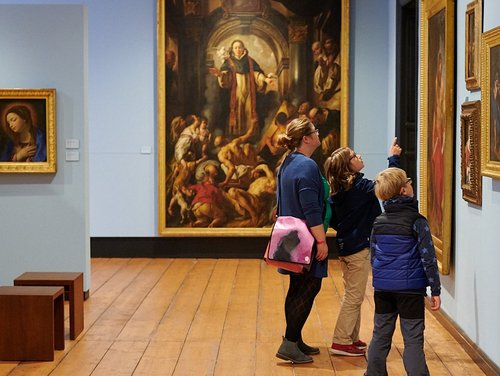 Eine Frau und zwei Kinder betrachten ein großes Gemälde.