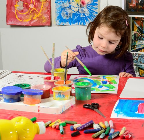 Ein Kindergartenkind malt mit Acrylfarben.